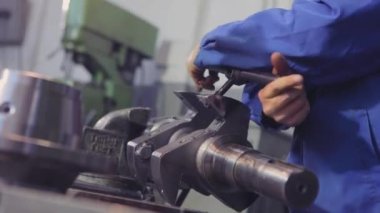 Başlatma ipliğine. Bir adam vida ipliğini metal bir parçadan keser. Metal bir parçayla çalışmak