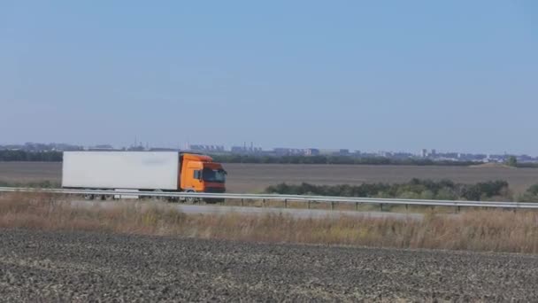 O camião está a conduzir na auto-estrada. O caminhão dirige na estrada em torno dos campos e árvores — Vídeo de Stock