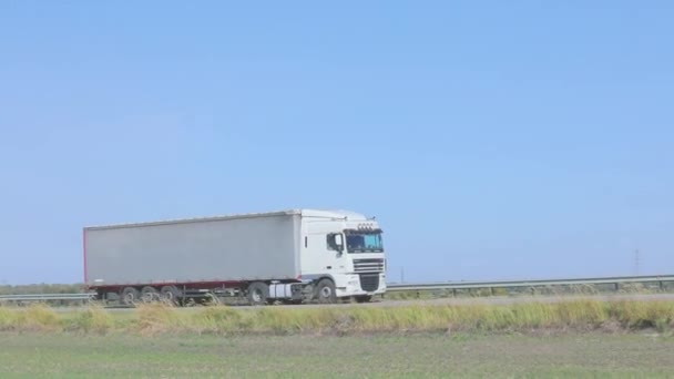 Biały wóz jedzie wzdłuż autostrady w słoneczną pogodę. Ciężarówka na autostradzie — Wideo stockowe