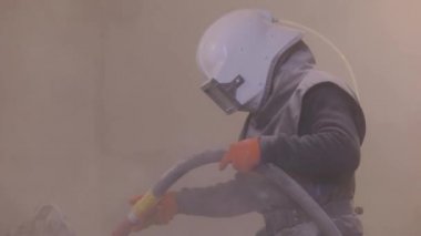 Adam ayrıntıları zımparalıyor. Kum patlaması metal parçaları. Kumlama silahı.