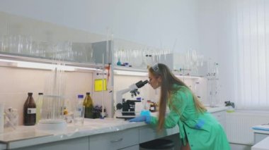 Laboratuvardaki kız. Laboratuvardaki güzel kız mikroskoptan bakıyor.