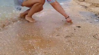 Dalgalar kuma gömülü olan kalbi alıp götürür. Kadın kuma bir kalp çizer. Bir kadın deniz kıyısında bir kalp çizer ve dalgalar tarafından sürüklenir..