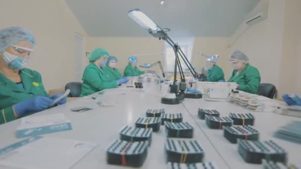 Робочий процес на фармацевтичній фабриці. Заводські робітники спакують таблетки. Масковані працівники . — стокове відео