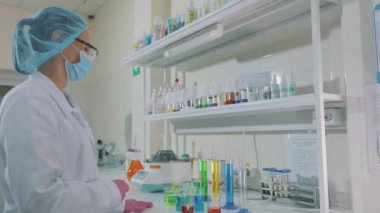Bir bilim adamı laboratuvarda deneyler yapıyor. Laboratuvarda iş akışı. Renkli mataralarla laboratuvar asistanı.