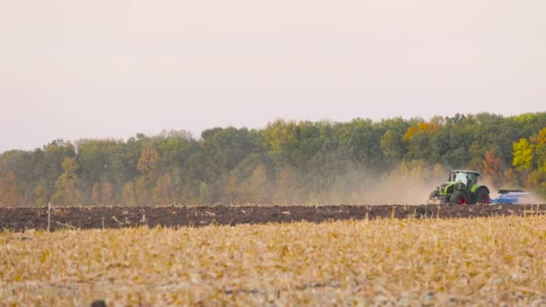 Groene trekker ploegt het veld. Tractor in het veld. Een moderne tractor ploegt het veld. — Stockvideo