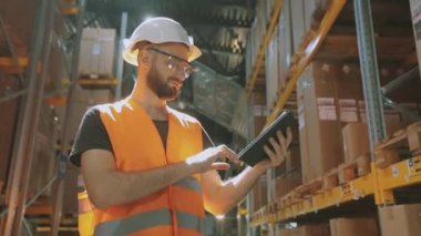 Depo müdürü depoyu kontrol ediyor. Modern bir depoda bir adam. Depoda kask takan bir işçi.