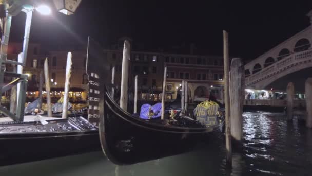 Góndolas amarradas en el Gran Canal cerca del Puente de Rialto por la noche, varias góndolas seguidas en el Gran Canal. Gran canal marco de noche — Vídeo de stock
