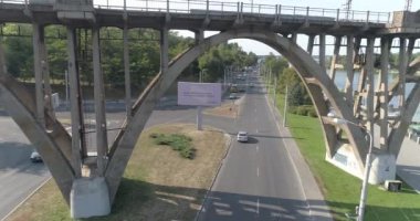 Şehrin üst manzarasında arabalar yol boyunca gider. Arabalar köprünün altından geçer. Köprü manzarasının altından geçen yolda birçok araba var. Araba trafiği.