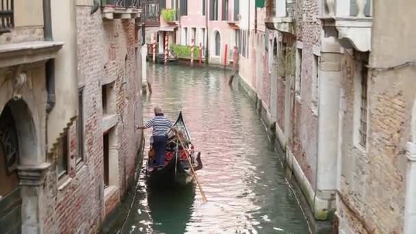 Gondel met toeristen in een prachtig smal kanaal in Venetië. Prachtig grachtengordel. Gondelaar rijdt toeristen Venetië, Italië. Romantische plek Venetië — Stockvideo
