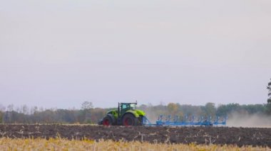 Traktör sahada. Modern bir traktör tarlayı sürer. Yeşil traktör tarlayı sürüyor
