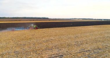 Traktör hava sahasını tarıyor. Traktör sahada çalışıyor. Sahada çalışan bir traktörün üzerinden uçmak. Bir traktörle sahanın üzerinden uç.