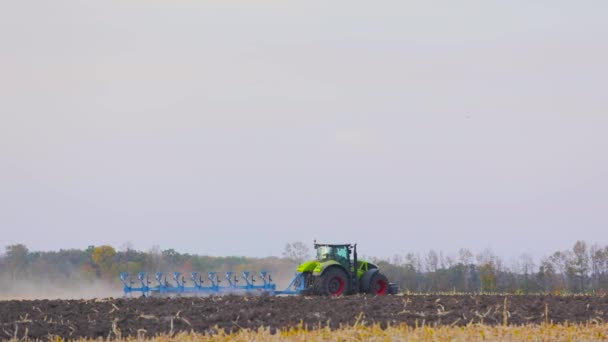 Современный трактор вспахивает поле. Зеленый трактор вспахивает поле. Трактор в поле. — стоковое видео