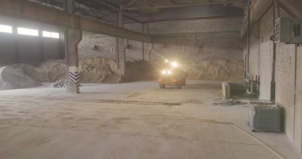Gelbe Planierraupe in einem Industriegebäude. Bulldozer auf Lager. Planierraupe schiebt Sand. — Stockvideo