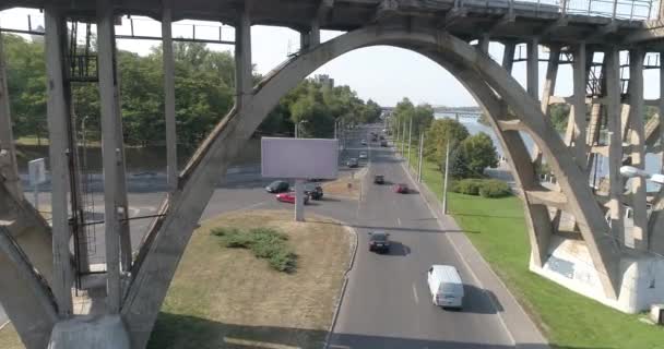 Los coches pasan por debajo del puente. Muchos coches en la carretera que pasa por debajo de la vista superior del puente. Tráfico de autos. Coches a lo largo de la carretera en la vista superior de la ciudad. — Vídeos de Stock