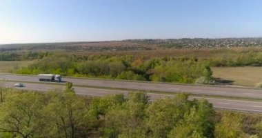 Kamyon yolda gidiyor, tarlalar arka planda. Malların kamyonla taşınması. Kamyon, tarımsal alanların ortasında yol boyunca gidiyor..