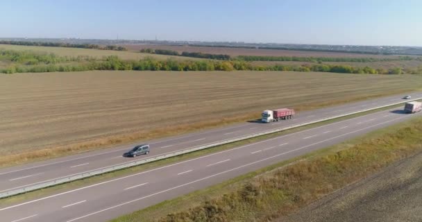 The truck drives along a long, straight road. The truck is driving along the road, nature is around. Wagon driving along the road drone shooting — Stock Video