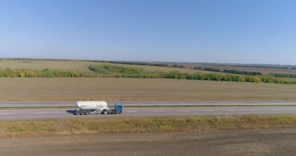 Ciężarówka jedzie po drodze, pola w tle. Ciężarówka jedzie wzdłuż drogi w środku pól rolniczych widok z góry. — Wideo stockowe