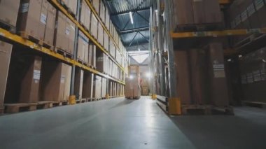 Stoklarda modern özel ekipmanlar var. Bir işçi hidrolik forkliftle yük taşır. Büyük modern depo.