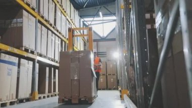 Stoklarda modern özel ekipmanlar var. Bir işçi hidrolik forkliftle yük taşır. Büyük modern depo.