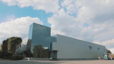 Büyük cam pencereli ofis binası. Bir kamyon modern bir binaya gidiyor. Modern bir ofis binasının yanında bir kamyon.