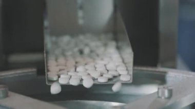 Yakın çekim tablet üretimi. İlaç fabrikası. Tablet üretimi için taşıma hattı