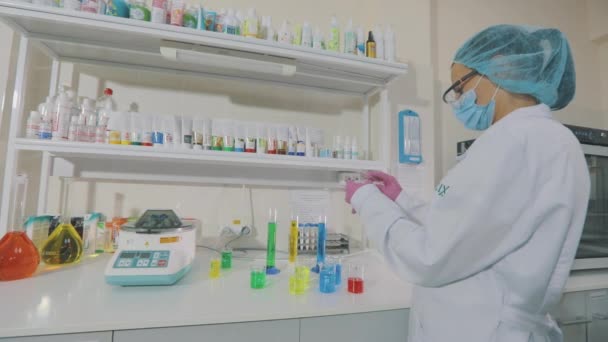Arbeitsablauf im Labor. Ein Wissenschaftler führt Experimente im Labor durch. Laborantin mit farbigen Fläschchen — Stockvideo