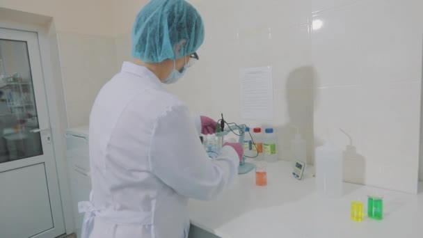 Un científico está realizando experimentos en el laboratorio. Flujo de trabajo en el laboratorio. Asistente de laboratorio con matraces de colores — Vídeos de Stock