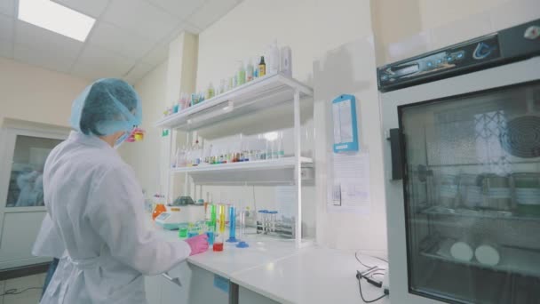 一位科学家正在实验室里进行实验.实验室的工作流程带彩色瓶的实验室助理 — 图库视频影像