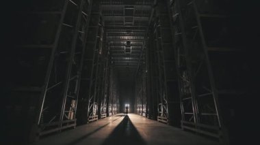 Fabrika deposunun ışıklarını yakmak. Fabrikada sabah bir adam depoda yürürken ışığı yanıyor.