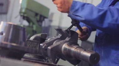 Bir adam vida ipliğini metal bir parçadan keser. Metal bir parçayla çalışıyorum. Başlatma ipliğine..