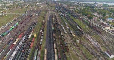 Çok sayıda yük treninin üzerinden uçun. Büyük bir kavşakta birçok tren var. Trenler demiryolu kavşağında duruyor.