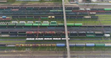 Yük trenleri ile büyük tren kavşağı manzaralı. Demiryolu kavşağındaki yük trenlerinin en üst görüntüsü. İstasyondaki trenlerin üzerinden uçuyor.