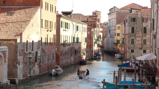 Canal en Venecia, un barco a motor navegando a lo largo de un canal en Venecia, Italia — Vídeo de stock