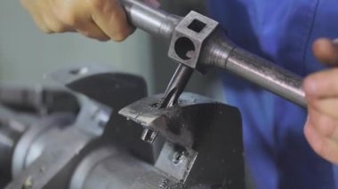 Bir adam vida ipliğini metal bir parçadan keser. Metal bir parçayla çalışıyorum. Başlatma ipliğine..