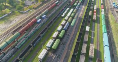 Trenler demiryolu kavşağındaki istasyona park edilmiş. Bir sürü renkli tren. Büyük sanayi demiryolu deposu.