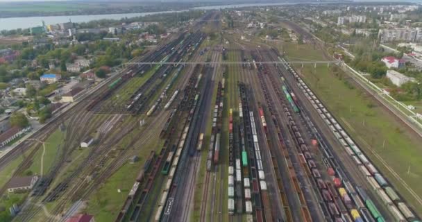 Treinen staan geparkeerd bij het depot bij de spoorwegkruising. Veel gekleurde treinen. Groot industrieel spoorwegdepot. — Stockvideo