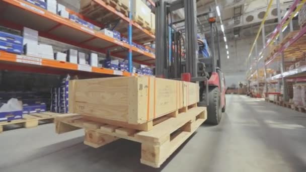Un carrello elevatore porta una scatola di legno. Un carrello elevatore con carico attraversa il magazzino — Video Stock