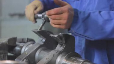 Başlatma ipliğine. Bir adam vida ipliğini metal bir parçadan keser. Metal bir parçayla çalışmak