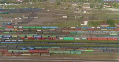 Demiryolu kavşağında bir sürü demiryolu manzarası var. Renkli trenler büyük bir tren istasyonunda duruyor.