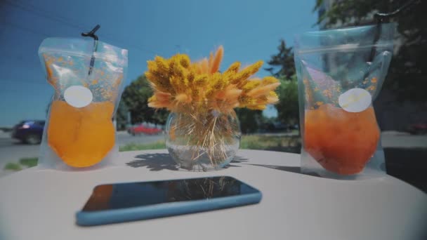 Frissen facsart gyümölcslé. Gyümölcslé az asztalon a városi közlekedés hátterében. Juice az asztalon egy étteremben a háttérben a város. — Stock videók