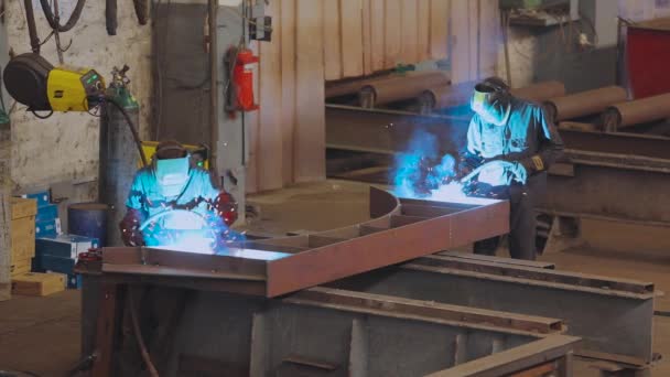 A worker in a factory welds a metal structure. Factory welder — Stock Video