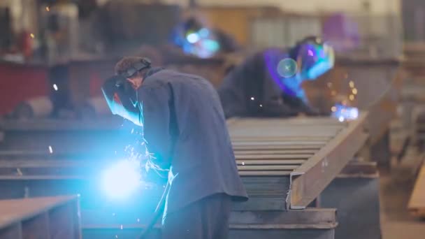 Soldador de fábrica. Un trabajador de una fábrica suelda una estructura metálica. — Vídeos de Stock