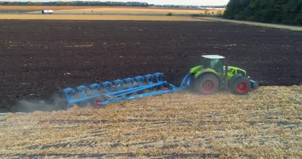 Vliegen over de trekker in het veld. Tractor werkt in het veld top-down zicht. Het proces van ploegen van het veld met een trekker — Stockvideo