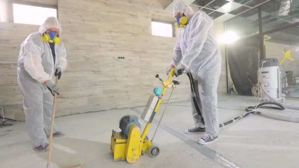 Profesjonaliści. Proces pracy na placu budowy. Pracownicy w kombinezonach ochronnych szlifują betonową podłogę. Pracownicy wykonują betonową podłogę — Wideo stockowe