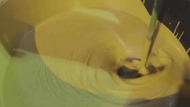 Ανάδευση μπογιάς σε κουβά. Ένα κοντινό πλάνο της κίτρινης μπογιάς αναδεύεται σε ένα κουβά — Αρχείο Βίντεο
