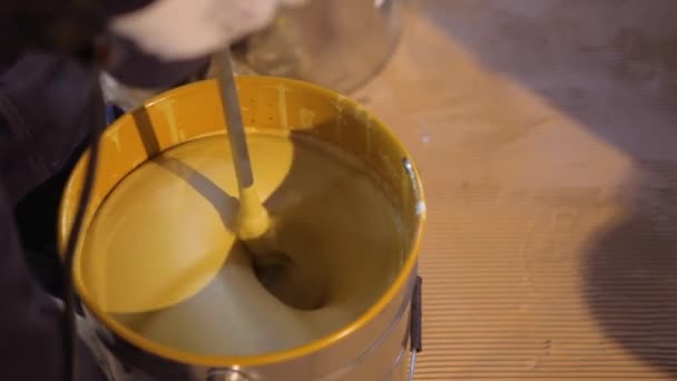 Un primer plano de pintura amarilla que se agita en un cubo. Agitar la pintura en un cubo. — Vídeos de Stock