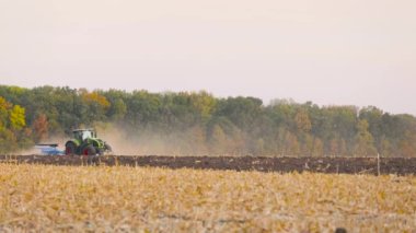 Traktör sahada. Modern bir traktör tarlayı sürer. Yeşil traktör tarlayı sürüyor