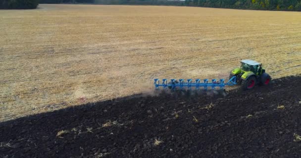 Atirando drone de um trator que trabalha no campo. O tractor trabalha no terreno. Fluindo um campo com um trator atirando de um drone. — Vídeo de Stock