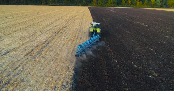 Vliegen over de trekker in het veld. Tractor werkt in het veld bovenaanzicht. De trekker ploegt het veld. — Stockvideo