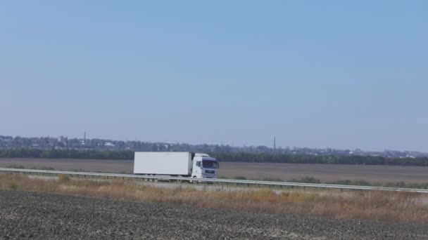 O camião está a conduzir na auto-estrada. O caminhão dirige na estrada em torno dos campos e árvores — Vídeo de Stock